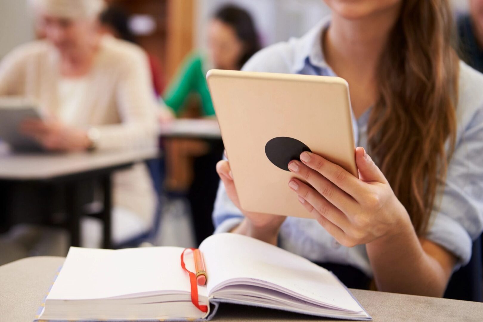 A woman holding an ipad in front of her face.