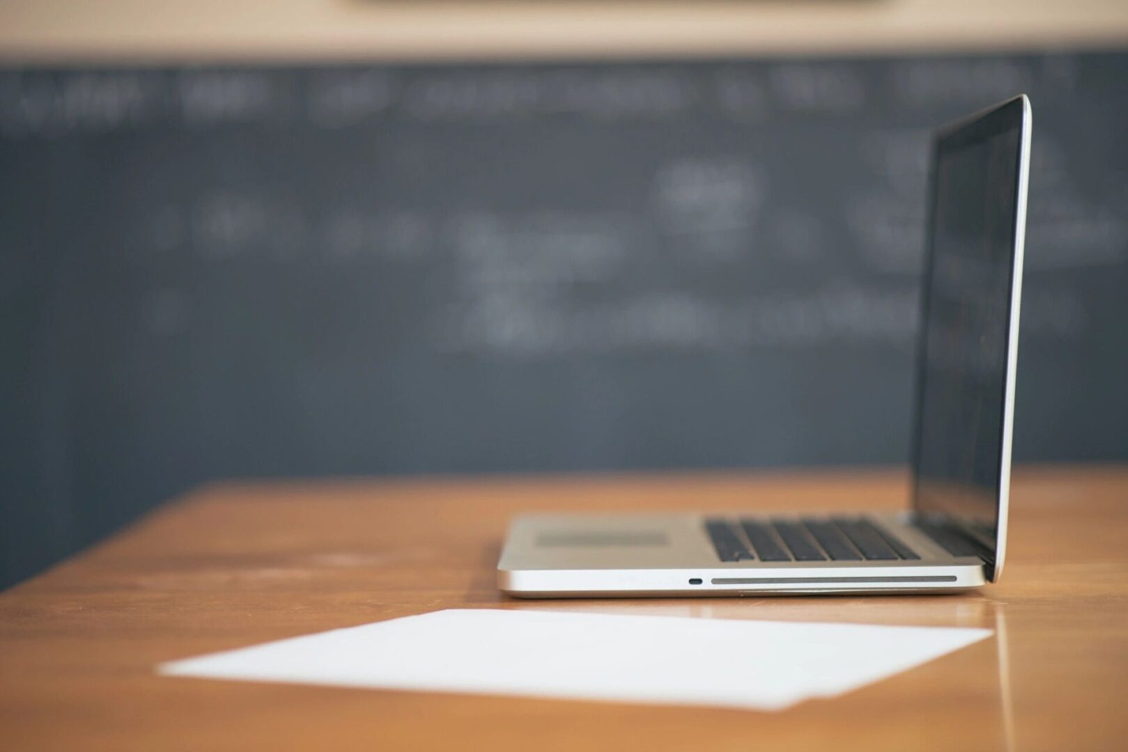 A laptop sitting on top of a wooden table.