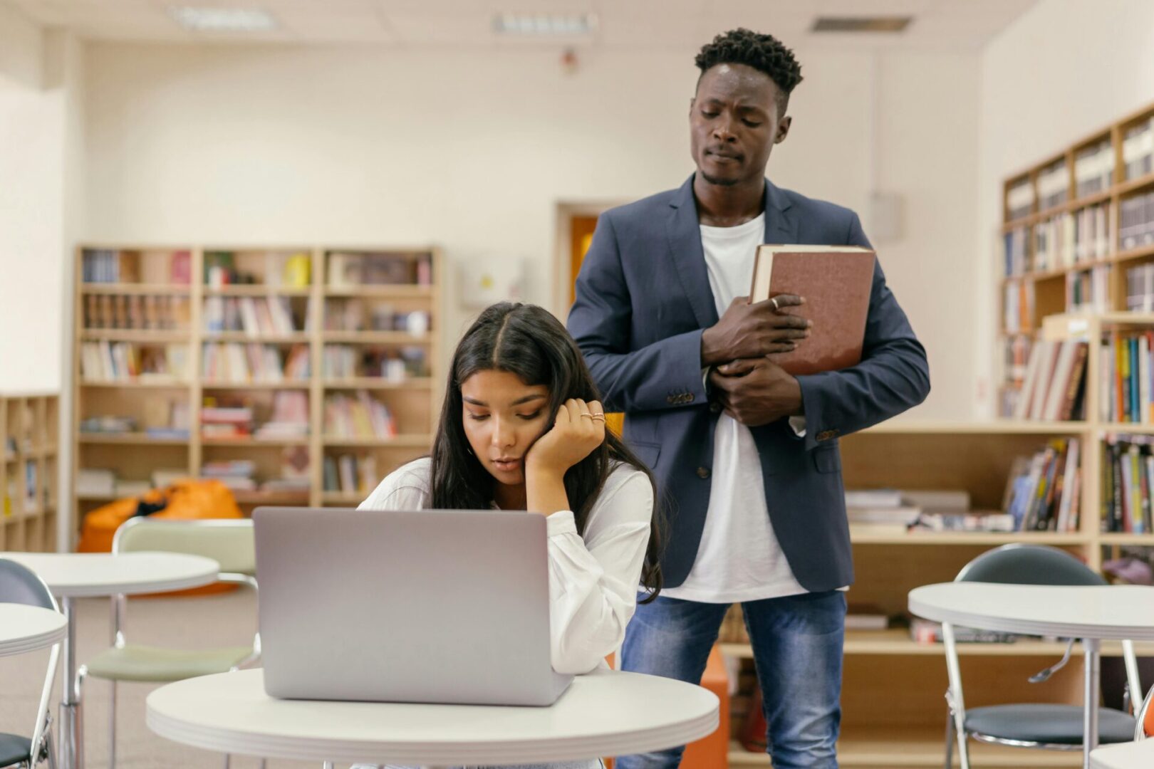 A man and woman standing in front of a laptop.