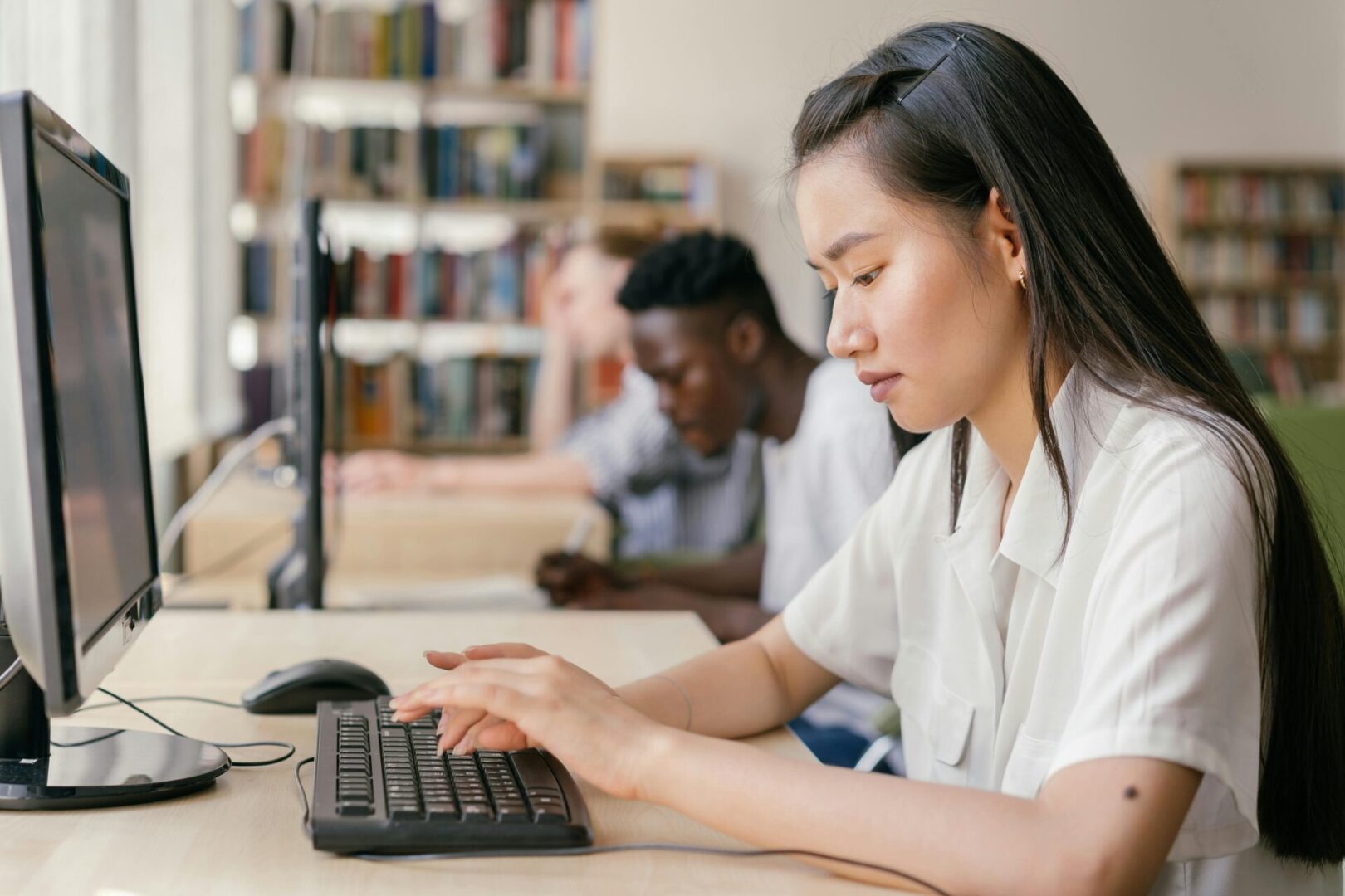 A woman is typing on the keyboard of a computer.