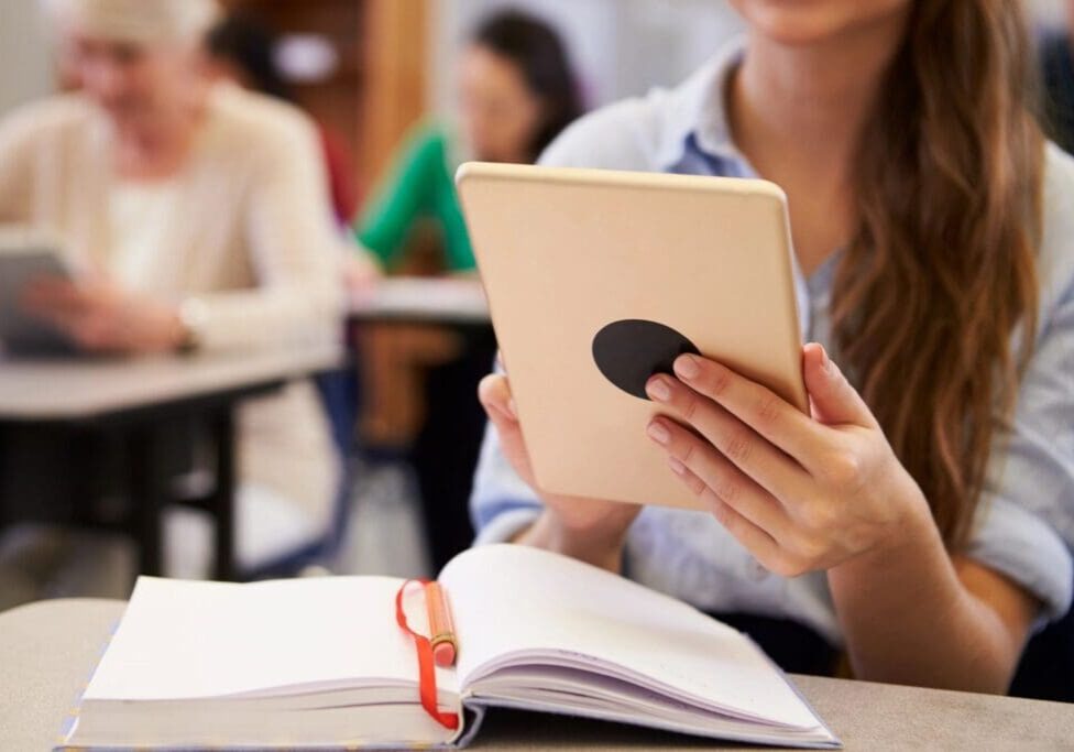 A woman holding an ipad in front of her face.