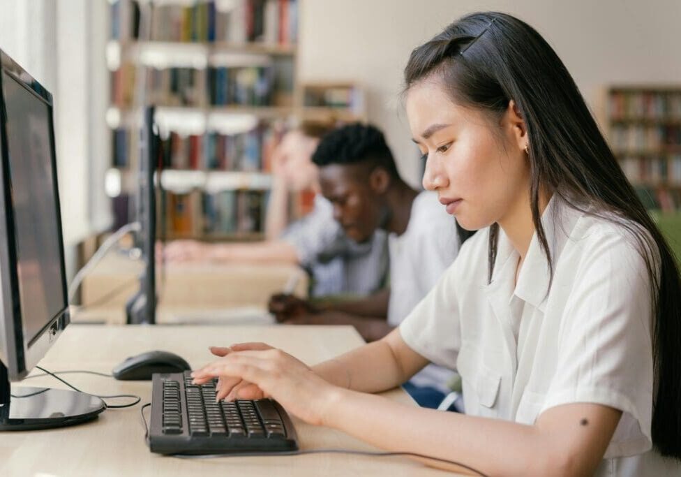 A woman is typing on the keyboard of a computer.